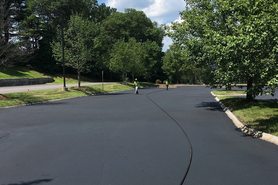 Sealcoaters applying second coat in parking lot